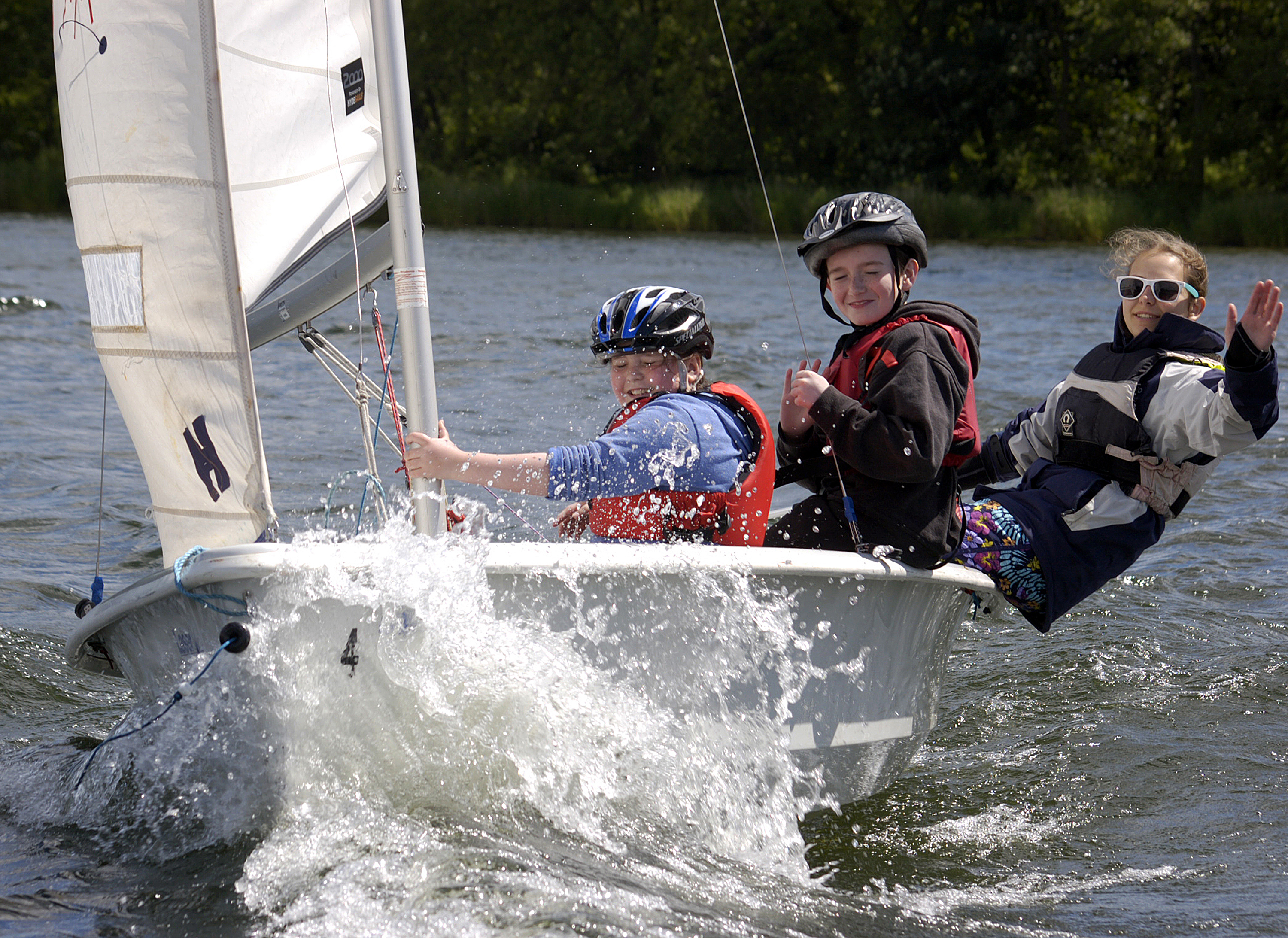 A group of 3 children are sailing in a boat.